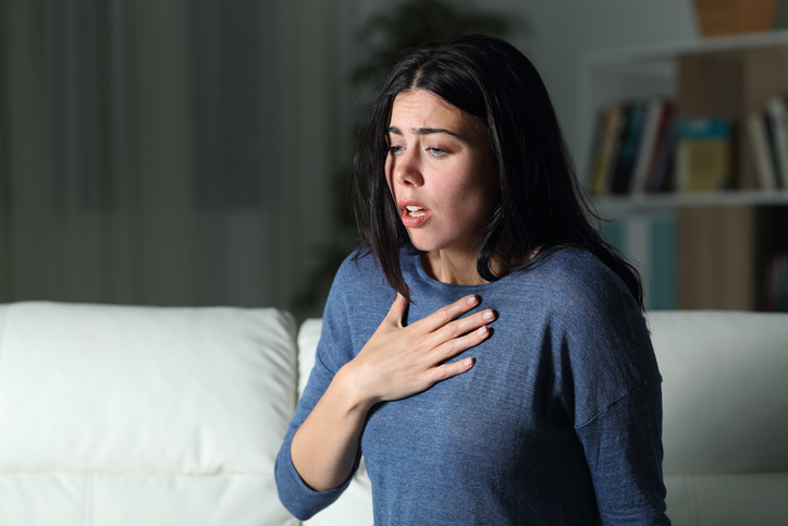 Woman suffering an anxiety attack alone in the night on a couch at home